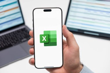 PRAG, CZECHIA - HAZİRAN, 2024: Arka planda insan eli ve dizüstü bilgisayarda akıllı telefon ekranında Excel logosu 