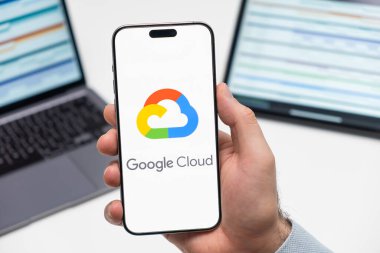 PRAG, CZECHIA - Temmuz 2024: Google Bulut logosu arka planda erkek eli ve dizüstü bilgisayarda akıllı telefon ekranında 
