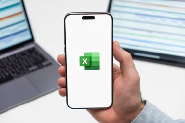 PRAG, CZECHIA - HAZİRAN, 2024: Arka planda insan eli ve dizüstü bilgisayarda akıllı telefon ekranında Excel logosu 