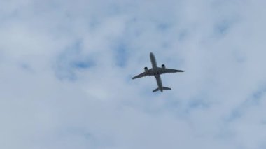 Havayolları uçakları sabit kanatlar ve odaklanmış yönleriyle gökyüzünü geçer. Uçak gökyüzündeki dağınık beyaz bulutların altında irtifa kazanıyor.