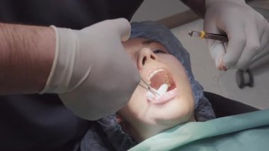 Profesyonel dikkatli bir şekilde hastaya sargı bezi yerleştirip kanamayı önlemek için ağzını açar. Doktor diş prosedürü sırasında forseps kullanarak malzemeyi yerine yerleştirir.