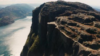 Preikestolen Lysefjord 'un üzerinde nöbet tutuyor. Uçurumun keskin kenarları ile aşağıdaki suyun pürüzsüz yansıtıcı yüzeyi arasındaki tezat