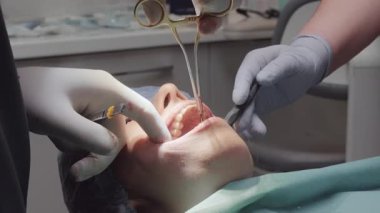 Forseps ameliyatında diş hekimliği yapıyor. Asistan, tedavi için gerekli koşulları sağlayan retraktör ve emme aracıyla alanı yönetir