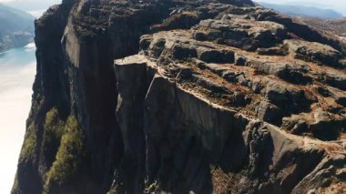 Kürsü Kayası, Lysefjord 'un yukarısındaki uçurumun heybetli kenarını gösteriyor. Norveç hava sahasında engebeli arazi ve berrak gökyüzünün altında parlayan su