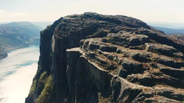 Muazzam kayalık yüzüyle Lysefjord 'a doğru ilerleyen muhteşem Preikestolen. Uzak dağların arasında fiyortlu Norveç manzarası
