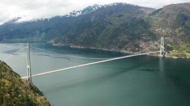 Hardanger Köprüsü, heybetli dağlar arasındaki derin fiyort boyunca uzanır. Asma köprünün zarif tasarımı Norveç 'in doğal çevresiyle çelişiyor