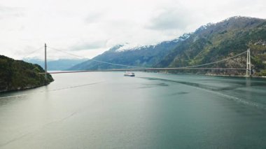 Hardanger Köprüsü fiyort üzerindeki sakin sularda büyük yelkenli yolcu gemisiyle zarifçe kemerlerle dönüyor. Görkemli dağlar Norveç 'in dingin güzelliğini özetliyor