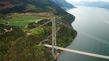 Hardanger Köprüsü kıyıda sütunlar var. Fiyort boyunca uzanan köprü yolu tünelde kayboluyor. Yeşil ve dolambaçlı yolların peyzaj özellikleri