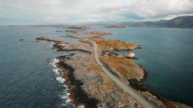Atlantik Okyanusu 'ndaki otobüs ve kamyon yolculuğu. Kayalık adaları yılan gibi geçen mühendislik harikası. Okyanusun derin mavi suları engebeli topraklarla tezat oluşturuyor.