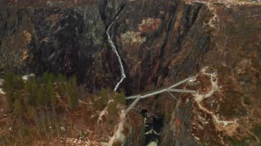 Voringsfossen şelalesi engebeli karanlık kaya yüzeyinden aşağı çağdaş köprüyle kanyon üzerinden geçiyor. Norveç 'te doğa harikasının dramatik boyutu