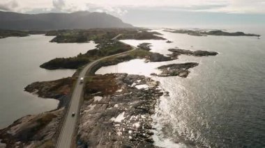 Atlantik Okyanusu yolu zarif bir şekilde küçük adalar boyunca zikzak çizer ve kokarcalar güneş ışığını suya yansıtır. Norveç 'te engebeli arazi ve bitki örtüsü