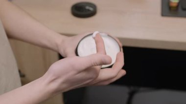 İnsan cildini nemlendirmek için kavanozdan krem alır. Erkek kişi evde vücut bakımı için kozmetik ürünler kullanıyor. Güzellik rutini