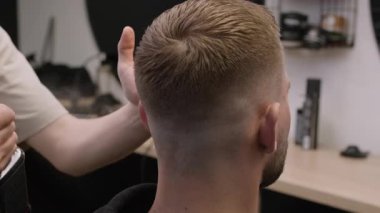 Kuaför, berber dükkanında saç modelleme ürününü müşterinin saçına sıkıyor. Berber kuaförde saç spreyi kullanıyor.