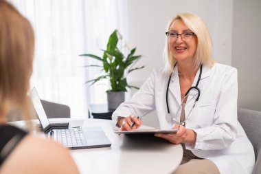 Kıdemli aile doktoru hastayı evde ziyaret ediyor, tıbbi geçmişi alıyor, tedavi planını açıklıyor. Yaşlı terapist genç bir kadını ziyaret ediyor, sorular soruyor, notlar yazıyor, terapi seçeneklerini tartışıyor.