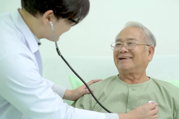 Elder Asian man sitting on the bed and talking to doctor about his physical injuries at his knees, elderly Asian man having a consulting with professional physical therapist or orthopedic doctor.