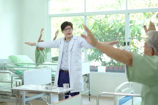 Elder Asian man practicing a physical therapy with professional therapist in hospital. Physiotherapist helping an elder man doing a physical therapy.
