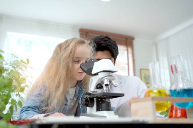 Laboratuvar önlüklü sevimli Asyalı kız deney yapmaktan ve bilim çalışmaktan zevk alıyor. Zeki Asyalı küçük çocuk, laboratuarda uzman bilim adamı ya da bilim araştırmacısıyla deneysel bir deney öğreniyor..