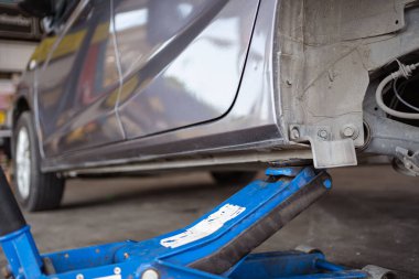 Hidrolik kriko kullanan teknisyen ya da tamirci arka tekerleği değiştirmek için arabayı kaldırır..