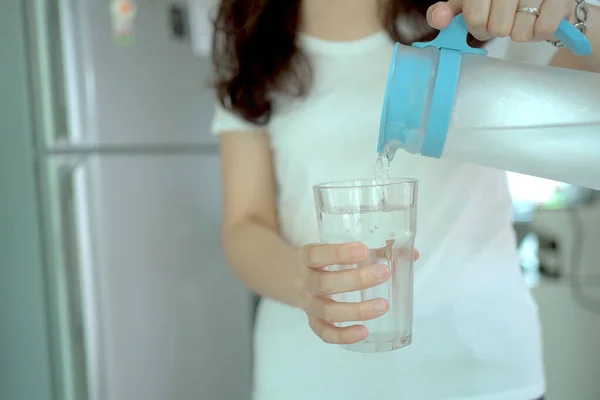 冷蔵庫を開けて水瓶や水瓶を手に入れ飲料ガラスに水を注ぐ — ストック写真