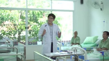 Doctor explaining about medical care and treatment to a group of senior elder patient in hospital ward.