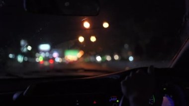 Unrecognizable woman pay attention on the road while driving a car in heavy rain. Woman driving in the night while raining.