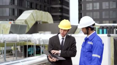 Professional Asian foreman and construction manager talking - discussing about building structure plant on the building rooftop. Businessman and construction engineer having a discussion.