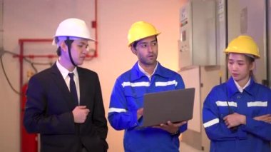 Asyalı elektrik mühendisi ekibinin portresi bir merkezi kontrol odasını inceliyor veya kontrol ediyor. Bakım odasında çalışan elektrik bakım mühendisleri..