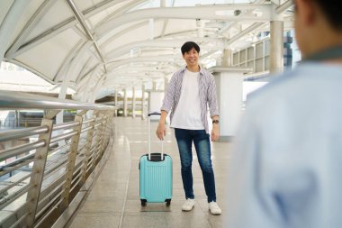 Babası seyahatten döndükten sonra neşeli Asyalı çocuk babasına koşuyor ya da gökyüzü tren istasyonunda. Mutlu Asyalı aile baba ve oğul kavramı.