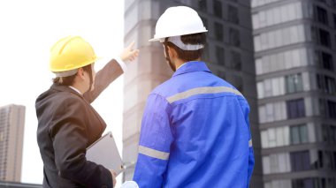 Profesyonel Asyalı ustabaşı ve inşaat yöneticisi yapı tesisi hakkında konuşuyor. İşadamı ve inşaat mühendisi tartışıyorlar..