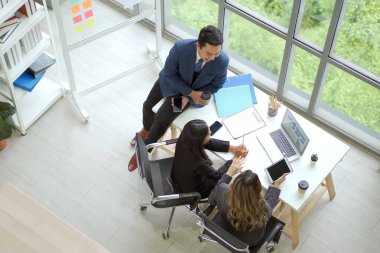 Asyalı kıdemli işadamı yıllık veya mali yıl iş planı toplantısını birlikte sunuyor. Neşeli yönetici işadamları ve iş kadınları işlerini tartışıyorlar..