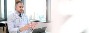 Tıbbi online video konferansı yoluyla hastayla konuşan profesyonel bir uzman doktor tablet ya da dizüstü bilgisayar, tele tıbbi servis konsepti. Ortopedi doktoru tıbbi danışmanlık yapıyor..