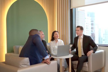 Çok uluslu yönetici iş adamları yıllık iş planı toplantısını birlikte yapıyor. Neşeli yönetici işadamları ve iş kadınları işlerini tartışıyorlar..