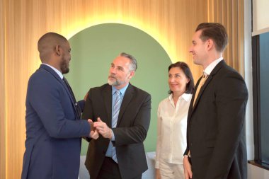 Çok uluslu iş adamlarından oluşan bir grup iş görüşmesi yapıyor ve el ele tutuşuyorlar. Mutlu milliyetçi iş adamı ve iş kadını tokalaşıyor ve el ele tutuşuyor..