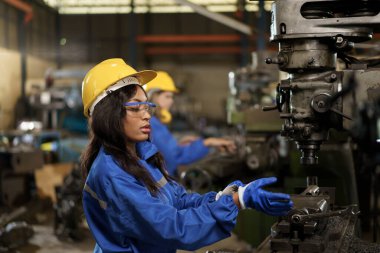 Makine mühendislerinden oluşan bir ekip fabrikada birlikte çalışıyor, mühendisler fabrikadaki bir metal makine sistemini inceliyor. Kadın ve erkek mekanik teknisyen bir makineyi tamir ediyor..