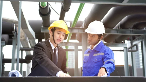 Professional Asian foreman and construction manager talking - discussing about building structure plant together. Businessman and construction engineer having a discussion.