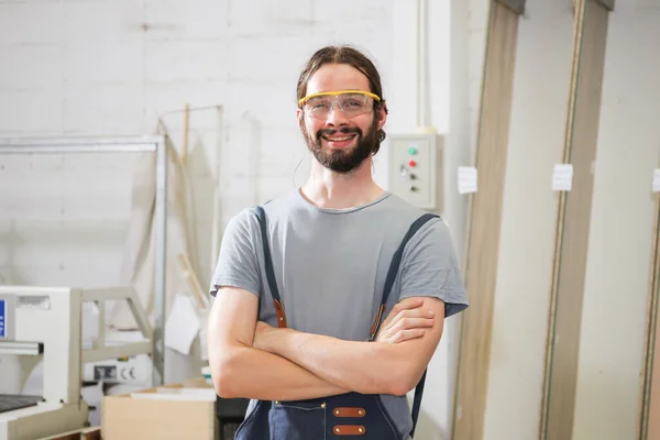 Professional male carpenter looking and smiling to camera. Happy caucasian white male carpenter posing for portrait during in the factory.