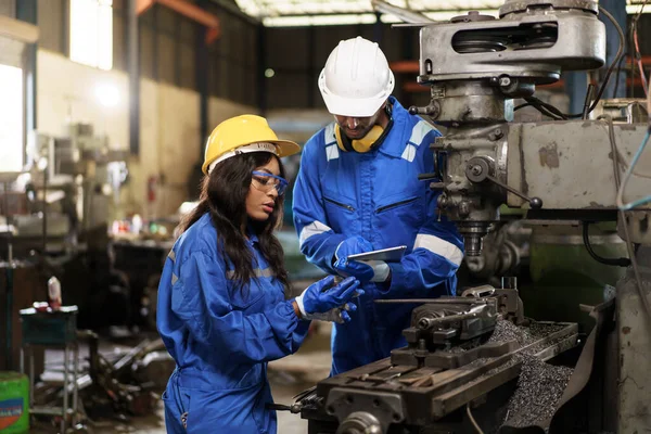 Team of mechanical engineer working together in the factory, engineers inspecting a metal machine system the factory. Female and male mechanical technician fixing a machines.