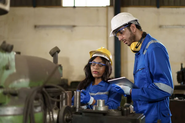 Team of mechanical engineer working together in the factory, engineers inspecting a metal machine system the factory. Female and male mechanical technician fixing a machines.