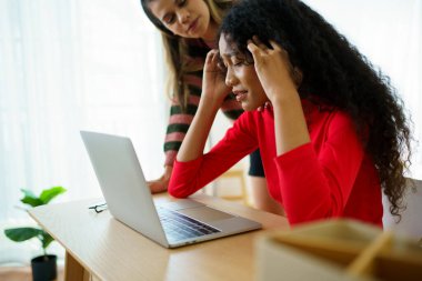 Mutsuz genç bir kadın. Defterin önünde kötü bir yüz ifadesi sergiliyor. Arkadaşı da onu cesaretlendirmeye geliyor..