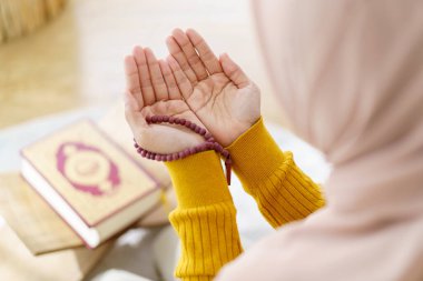 Güzel Asyalı genç Müslüman kadın evinde yerde oturup kutsal bir tanrı için dua ediyor..