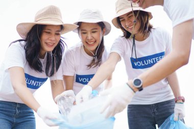 Bir grup Asyalı genç gönüllü parktaki plastik şişe çöplerini toplamaya ya da toplamaya yardım ediyor. Sürdürülebilirlik ve çevre koruma kavramı.