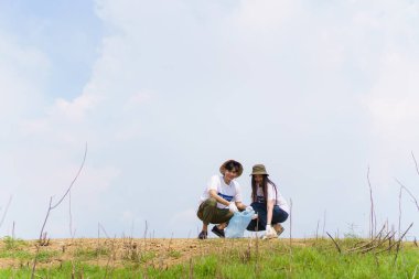 Bir grup Asyalı genç gönüllü parktaki plastik şişe çöplerini toplamaya ya da toplamaya yardım ediyor. Sürdürülebilirlik ve çevre koruma kavramı.