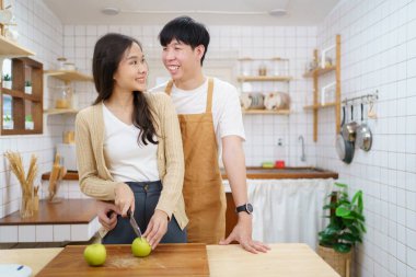 Mutlu Asyalı çift mutfakta organik sebze salatası yapıyor. Yemek bıçağı kullanan kadın sebze kesiyor. Sağlıklı yeme kavramı.