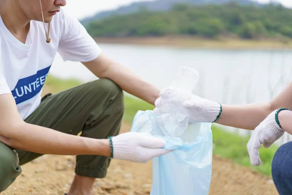 一群亚洲年轻人志愿帮助在公园的地上收集或捡拾塑料瓶垃圾 可持续发展和环境保护概念 — 图库照片