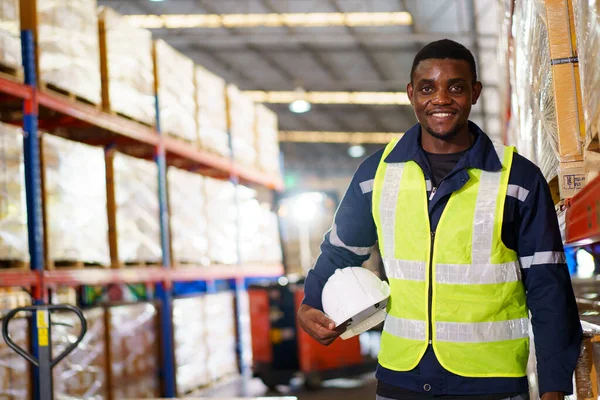Happy cheerful African - American black ethnicity male warehouse staff smiling to camera portrait. Professional storage warehouse worker or engineer looks and smiles to camera.
