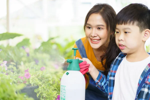 快乐的亚洲女人和小男孩一起在温室里种花 心满意足的小男孩喜欢和妈妈一起在温室里种树浇水 — 图库照片