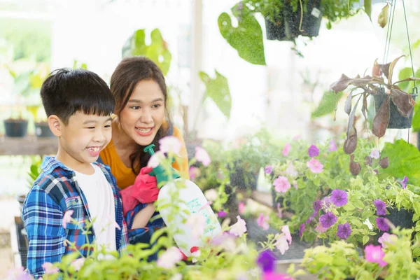 快乐的亚洲女人和小男孩一起在温室里种花 心满意足的小男孩喜欢和妈妈一起在温室里种树浇水 — 图库照片