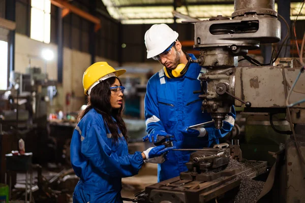 Makine mühendislerinden oluşan bir ekip fabrikada birlikte çalışıyor, mühendisler fabrikadaki bir metal makine sistemini inceliyor. Kadın ve erkek mekanik teknisyen bir makineyi tamir ediyor..