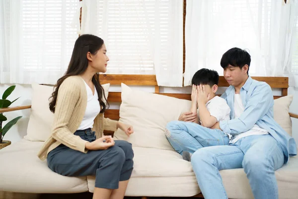 unhappy Asian family, critical problem of father and mother arguing with their daughter sitting and crying on the bed. Parent problem - social issue. Divorce family and sadness.