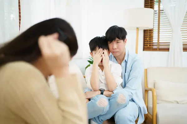 unhappy Asian family, critical problem of father and mother arguing with their daughter sitting and crying on the bed. Parent problem - social issue. Divorce family and sadness.